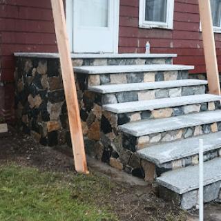 A newly constructed stone staircase leading up to a front door, featuring a rustic design.