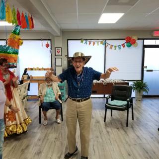 A joyful person wearing a hat celebrates indoors with festive decorations.
