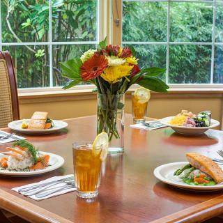 A beautifully set dining table with meals and a floral centerpiece.