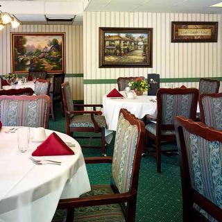 A well-decorated restaurant dining area with elegantly set tables, featuring white tablecloths and red napkins.