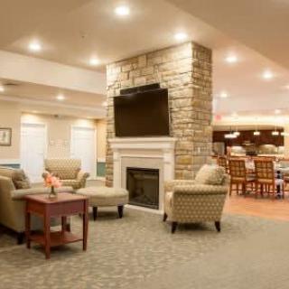 A cozy living room with a stone fireplace, comfortable seating, and a mounted television.