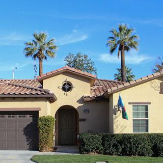 A suburban house with palm trees and a clear blue sky.