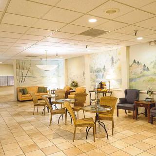 A cozy lobby with seating arrangements, featuring tables and chairs, decorated with artwork on the walls.