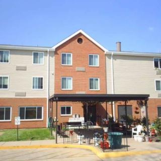 A three-story residential building with a brick facade and an entrance covered by an awning on a clear day.