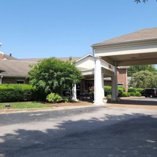 A hotel entrance with a covered driveway and landscaped surroundings.