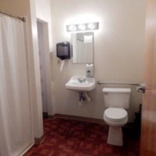 A bathroom featuring a sink, toilet, and shower with bright lighting.