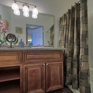 A modern bathroom with a wooden vanity, mirror, and a patterned shower curtain.