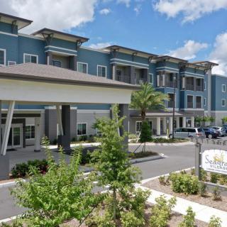 A modern residential building with landscaped surroundings and a parking area.