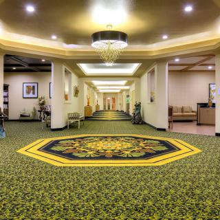 A spacious hotel lobby with a patterned carpet and ceiling lights.