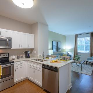 A modern open floor plan apartment with a kitchen and living room area.