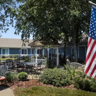 A peaceful garden patio with a gazebo and an American flag.