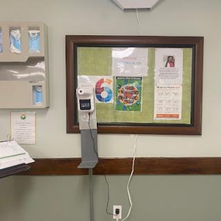 A view of a patient room in a hospital featuring medical equipment and a bulletin board.