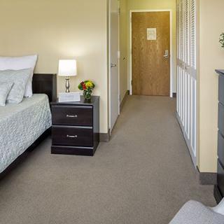 A comfortable and neatly arranged hotel room with a bed, nightstand, and soft lighting.