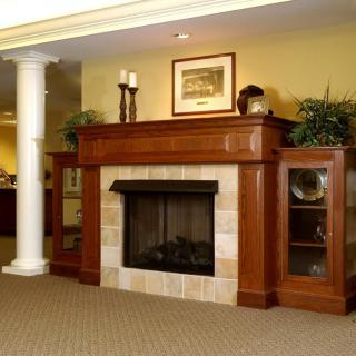 A cozy living room with a wooden mantel and fireplace, adorned with decorative items.
