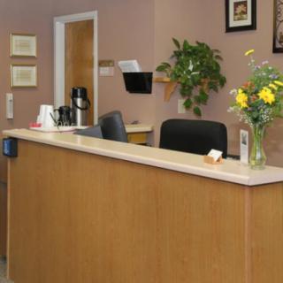 An office reception desk with a vase of flowers and seating area.