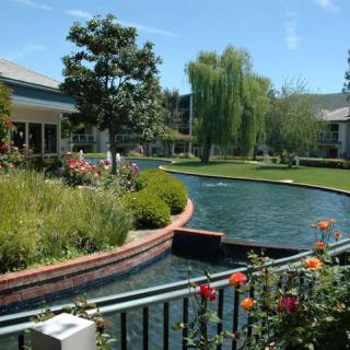 A beautifully landscaped garden with a pond and surrounding buildings.