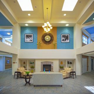 A spacious lobby with elegant interior design featuring a central chandelier, comfortable seating, and a fireplace.