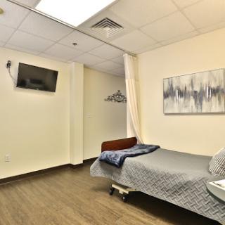 A clean and modern hospital patient room featuring a bed, a television, and minimal decor.