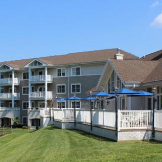 A residential apartment building with balconies and a well-maintained lawn under a clear blue sky.
