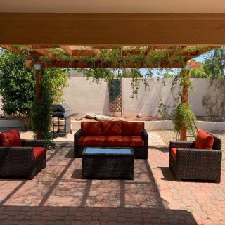 An inviting outdoor patio with a pergola, comfortable seating, and lush greenery.