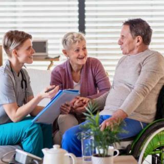 A nurse consulting with elderly patients, one in a wheelchair.