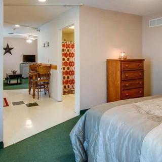 A cozy bedroom with a view into a connected living area, featuring a bed, dresser, and modern decor.