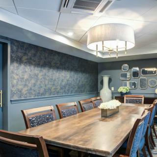 A stylish conference room with a large wooden table, elegant chairs, and decorative wall art.