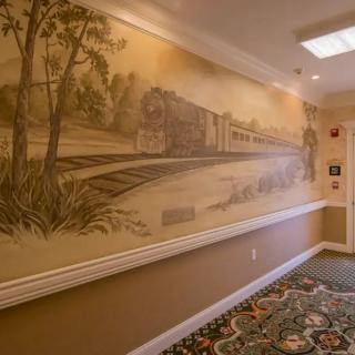 A sepia-toned mural of a train on the wall in a hallway.
