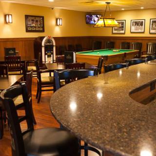 A cozy bar interior featuring a pool table, seating area, and a jukebox.