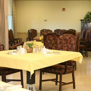 A neatly arranged dining area with tables covered in yellow tablecloths.