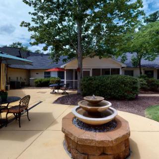 A tranquil outdoor patio featuring a central fountain surrounded by seating and lush greenery.
