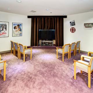 A cozy viewing room featuring comfortable seating and a television, adorned with classic film posters.