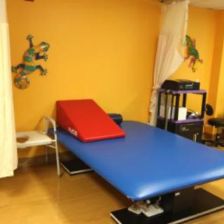 A therapy room with a blue massage table and colorful wall decorations.