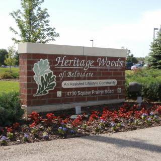 Entrance sign for Heritage Woods of Sheridan surrounded by landscaping.