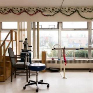 A physical therapy room with medical equipment and a large window view.