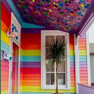 A vibrant and colorful interior showcasing a rainbow-striped wall and a beautifully painted ceiling adorned with butterflies.
