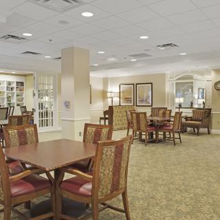 Spacious dining area with multiple tables and chairs, featuring elegant interior design and carpeted flooring.