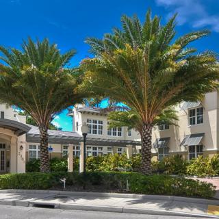 A sunny day view of a residential building with palm trees in front.