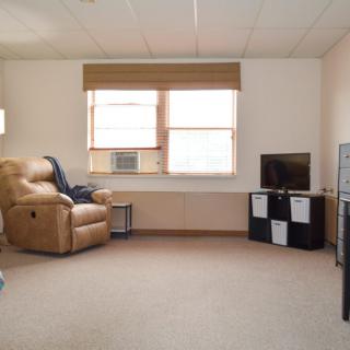 A cozy living room with a recliner, television, and window.