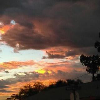 A vibrant sunset with dramatic clouds and silhouetted trees.