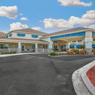 A modern building with an entrance driveway and a clear sky with clouds.