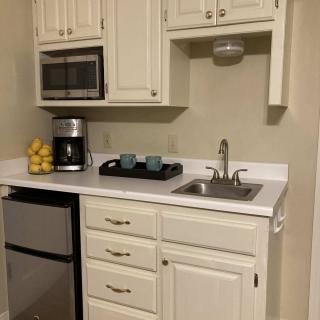 A compact kitchen area with a microwave, coffee maker, sink, and mini fridge.