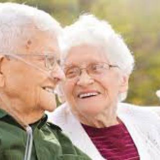 An elderly couple smiling and enjoying time together outdoors.