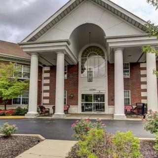 A grand entrance of a brick building with white columns and landscaped surroundings.