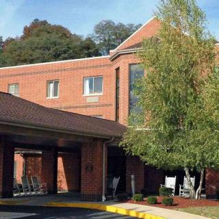 A brick building with a covered entrance and surrounding trees.