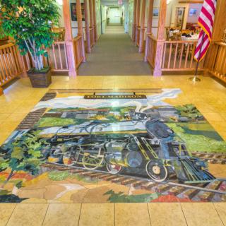 A stunning 3D art illusion of a train decorates the floor of a hallway.