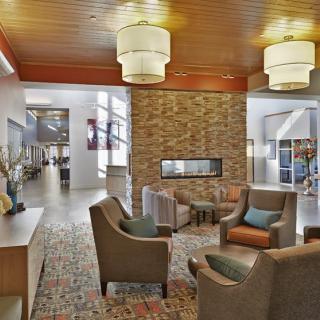 A modern lobby with comfortable seating and a central fireplace.