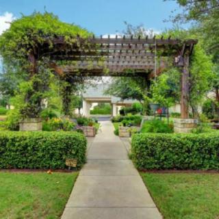 A beautiful garden with a pergola and a pathway surrounded by lush greenery.