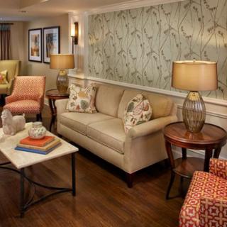 A cozy and stylish living room with a beige sofa, patterned wallpaper, and elegant lighting.