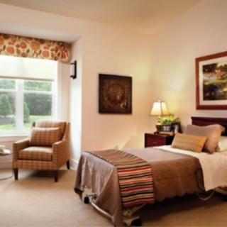A cozy bedroom with a single bed, armchair by the window, and elegant decor.